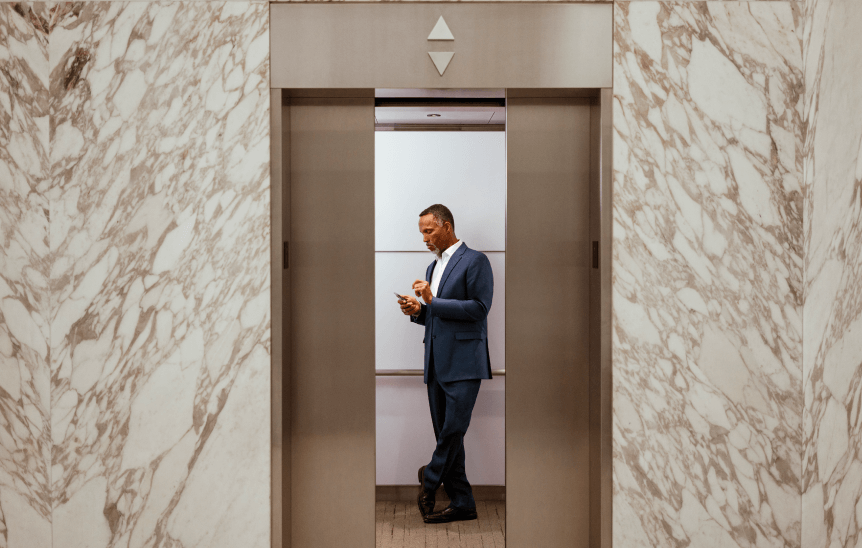 A man using his phone while on an elevator