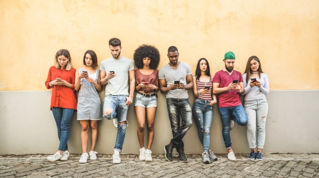 multiracial friends using smartphone against wall at university college backyard young people addicted by mobile smart phone technology concept with always connected millennials filter image