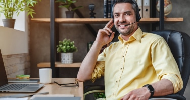 Male call centre agent wearing headset working from home