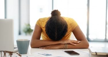 Shot of a young businesswoman with her head down on her office desk