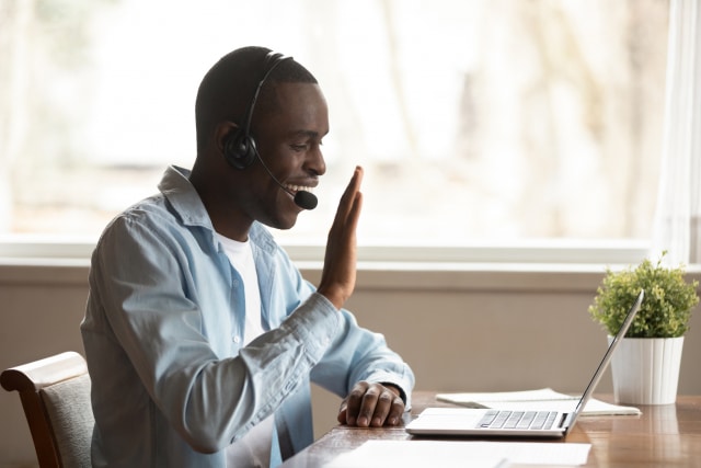 Man wearing headset starting video call greeting colleagues