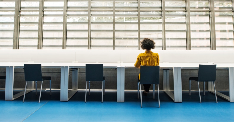 woman sitting at one chair in a row of chairs in an otherwise empty office