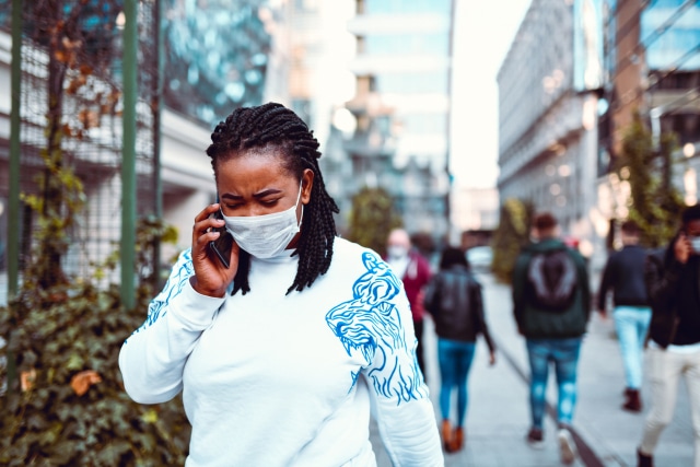 african female with surgical mask outside using phone during coronavirus outbreak