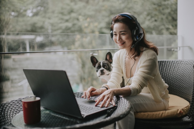 asian chinese beautiful woman work from home having virtual meeting with colleague at balcony with her pet french bulldog wearing headset