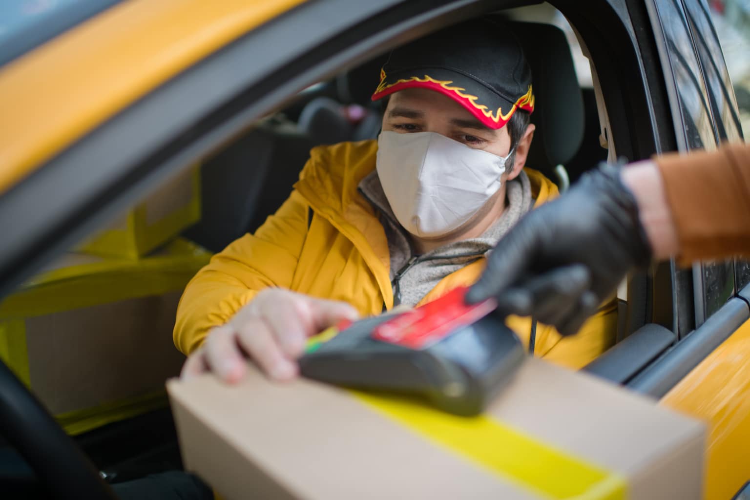 Delivery man with protective mask and gloves delivering parcels during lockdown and pandemic and holding mobile contactless payment machine-495