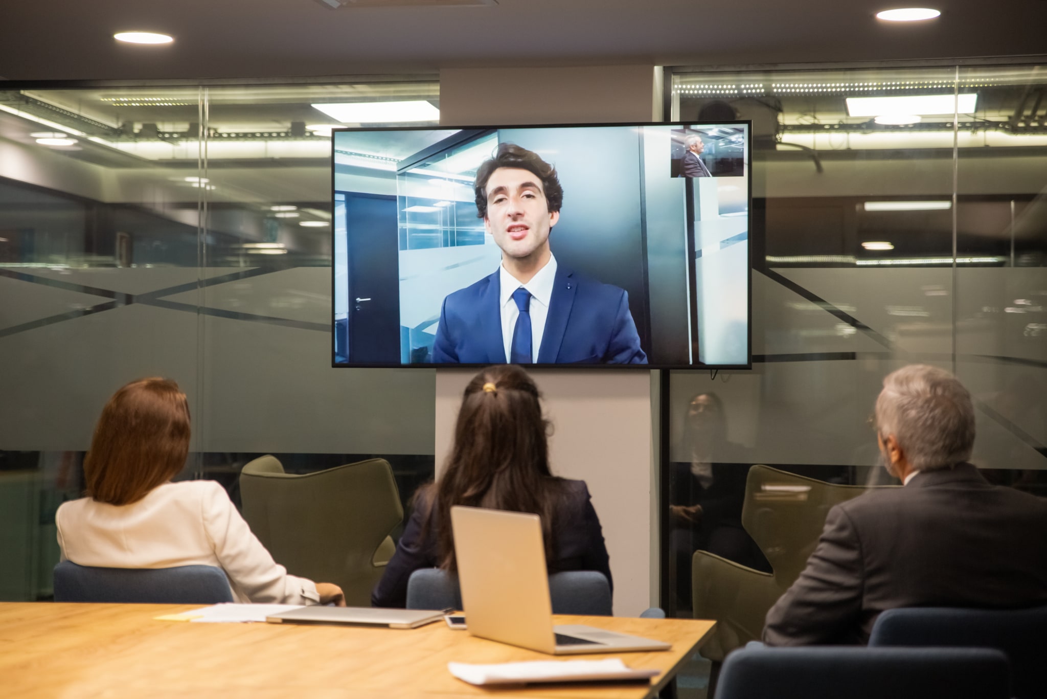 Business people looking at monitor screen during video conference in office.