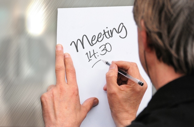 man writing the meeting schedule on white paper