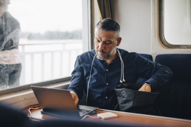 Confident male entrepreneur using laptop by window while traveling in ferry-344