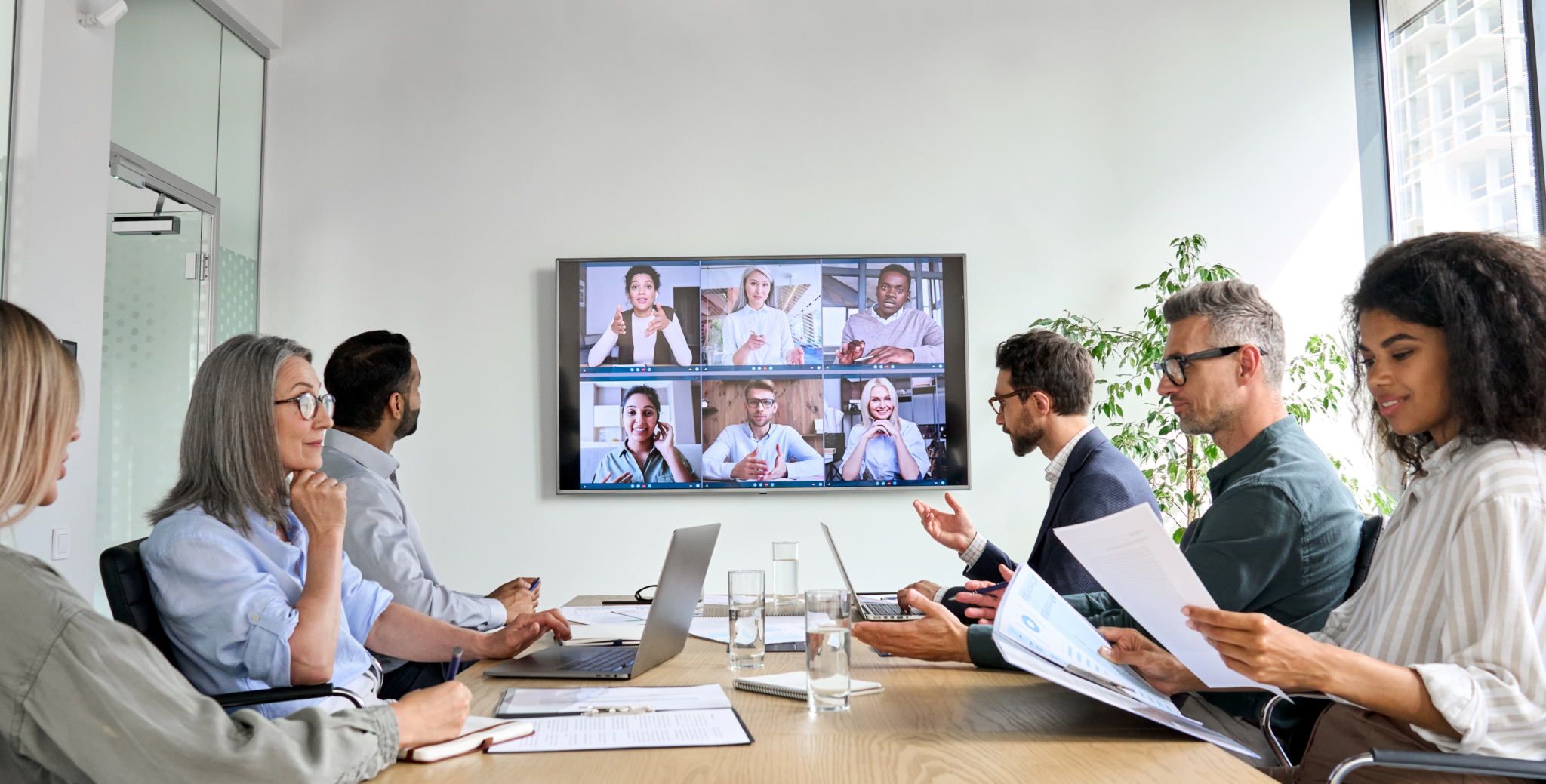Diverse employees on online conference video call on tv screen in meeting room.-708